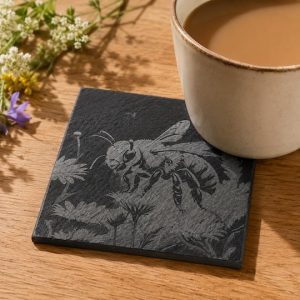 Engraved slate drinks coaster featuring a detailed bee and floral design